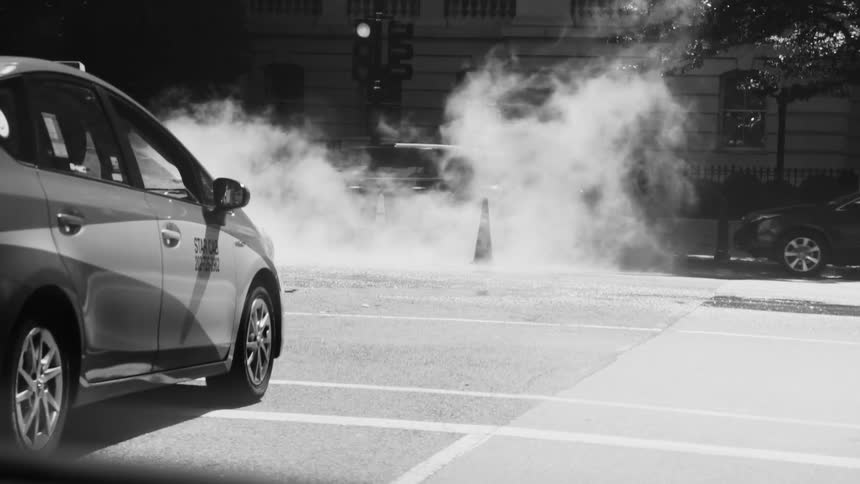 Busy street with vehicle traffic and smoke rising from the ground