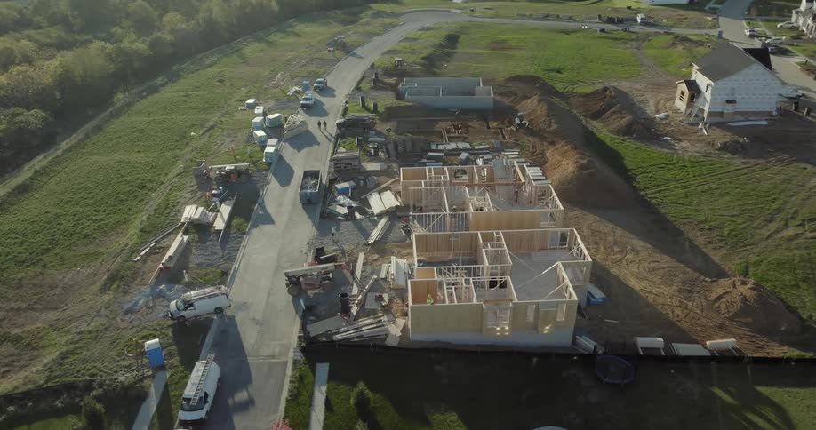 An aerial view of a residential construction site with several houses in various stages of completion