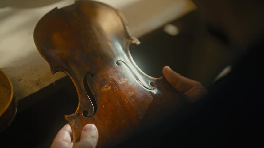 Hands checking the production of a violin