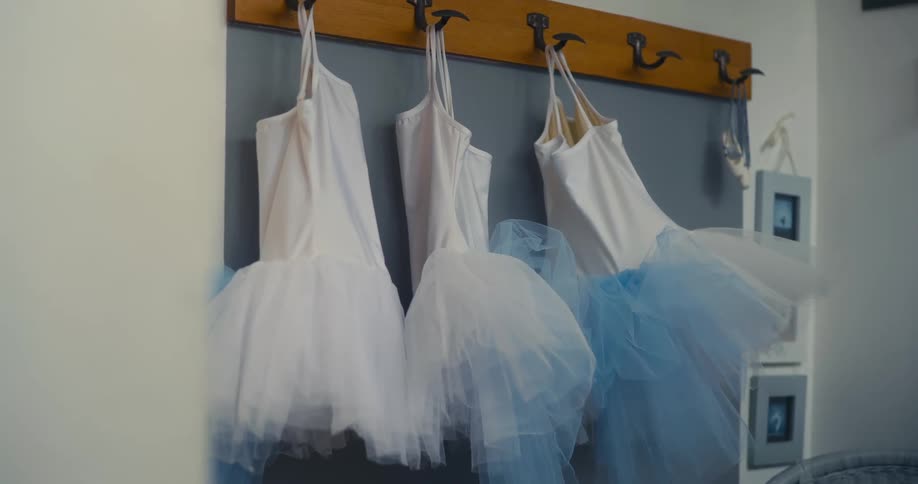Three childrens ballet dresses hanging on the wall