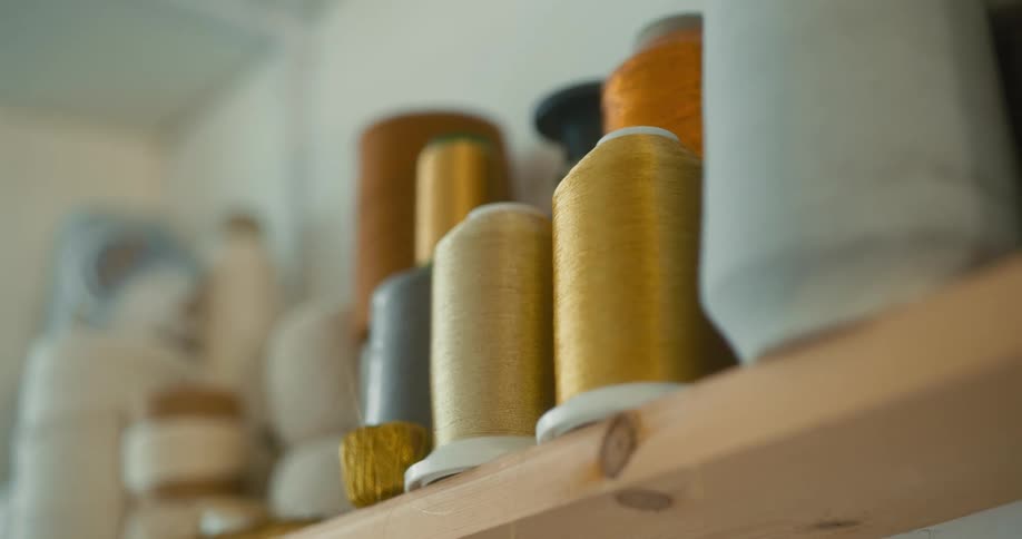 Variety of spools of sewing thread in different colors and sizes arranged on shelves