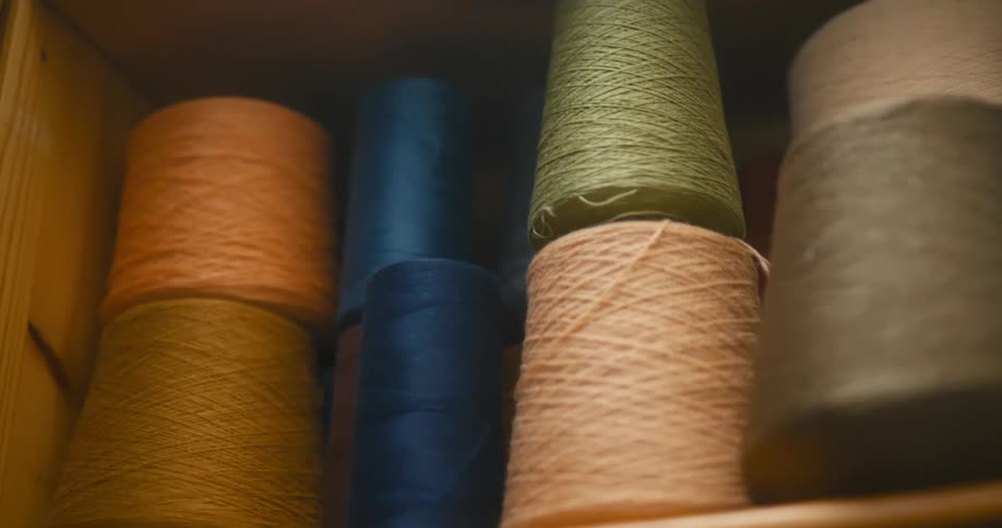 Hands picking up rolls of yarn of different colors