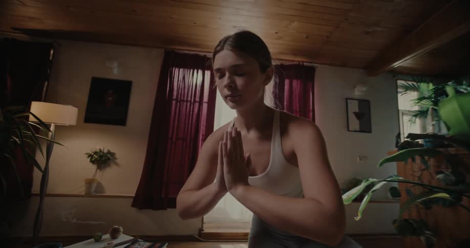 A woman strikes a yoga pose on a mat in a living room