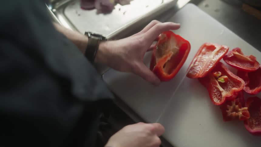 Hand with a knife cutting bell pepper
