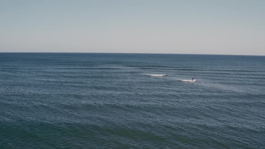 Surfers catch ocean waves far away from land