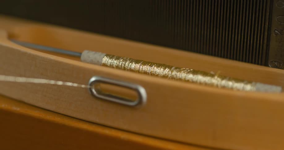 Gold thread is unwinding from the spindle
