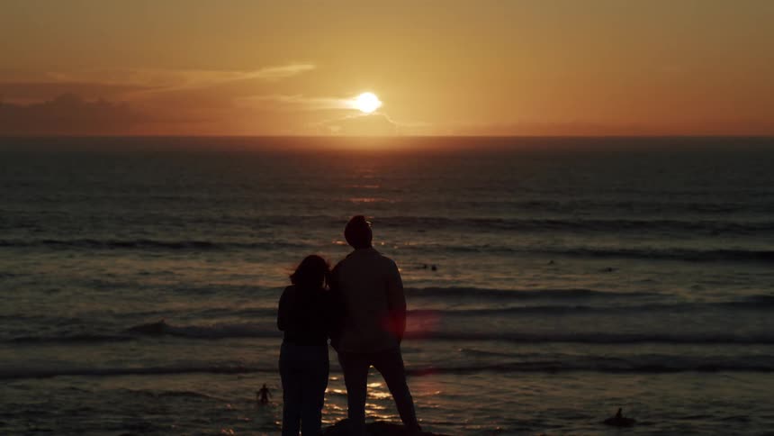 Silhouette of a young couple looking at the sunset over the ocean