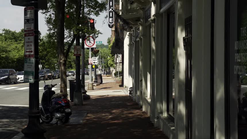 Moving point of view of a city sidewalk with the street next to it