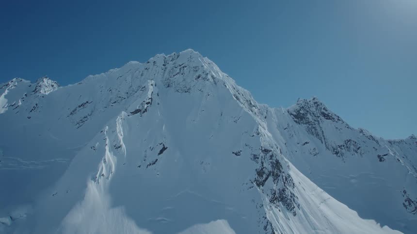 Snowcovered mountains under a clear blue sky at midday