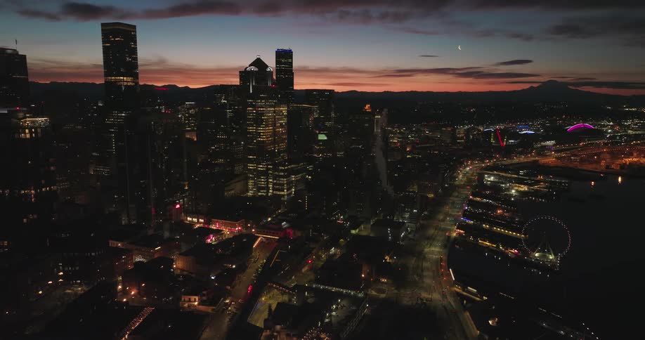 Wispy clouds and a crescent moon paint the sky at sunrise over downtown Seattle