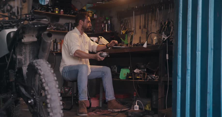 Mechanic in a garage holding a metal part