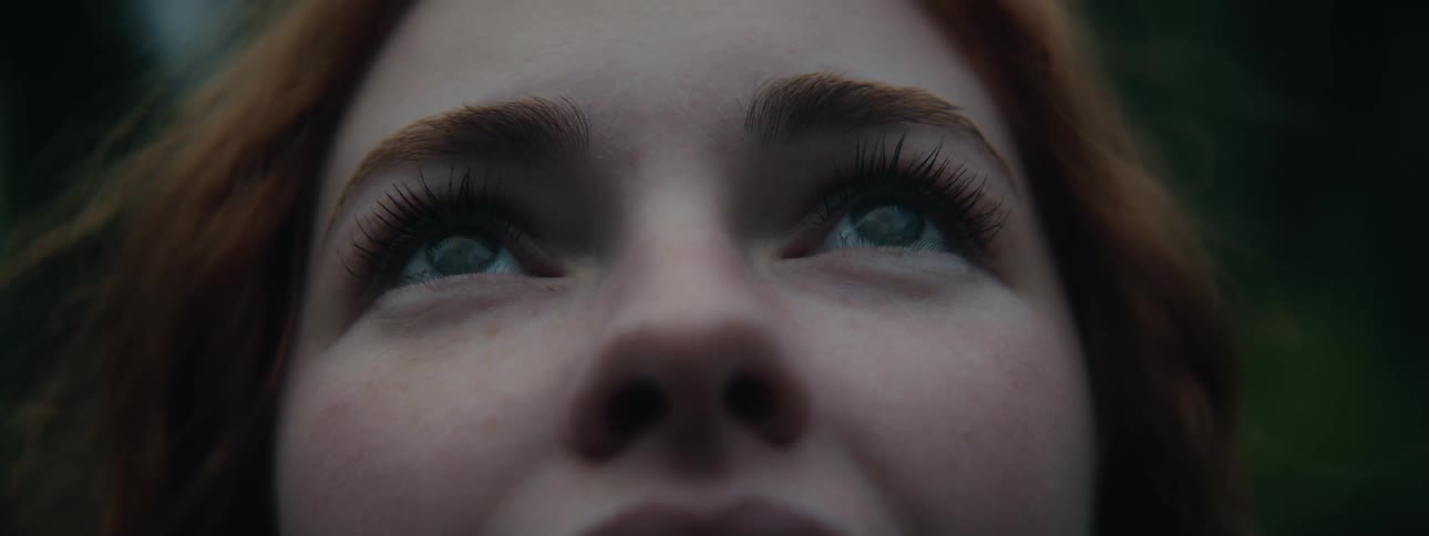 Closeup of a pale woman with red hair looking up