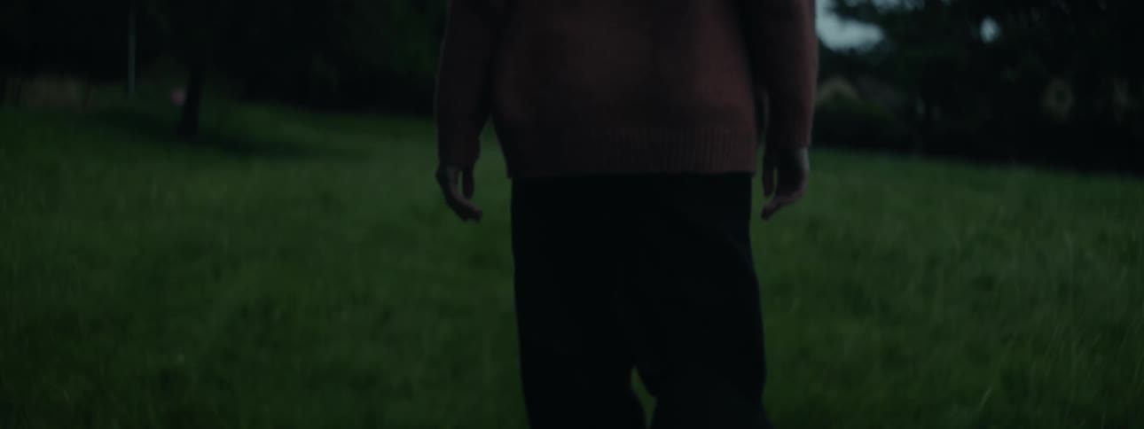 View of a person from behind walking through the grass