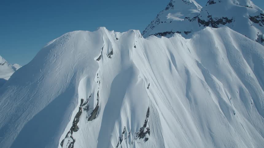 Aerial view of snowy mountains against a cloudless blue sky