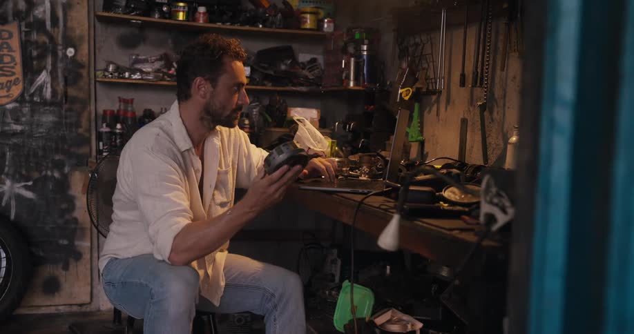 Man sitting looking at a cylindrical metal piece