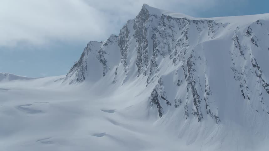 Clouds float over mountains covered in heavy snow