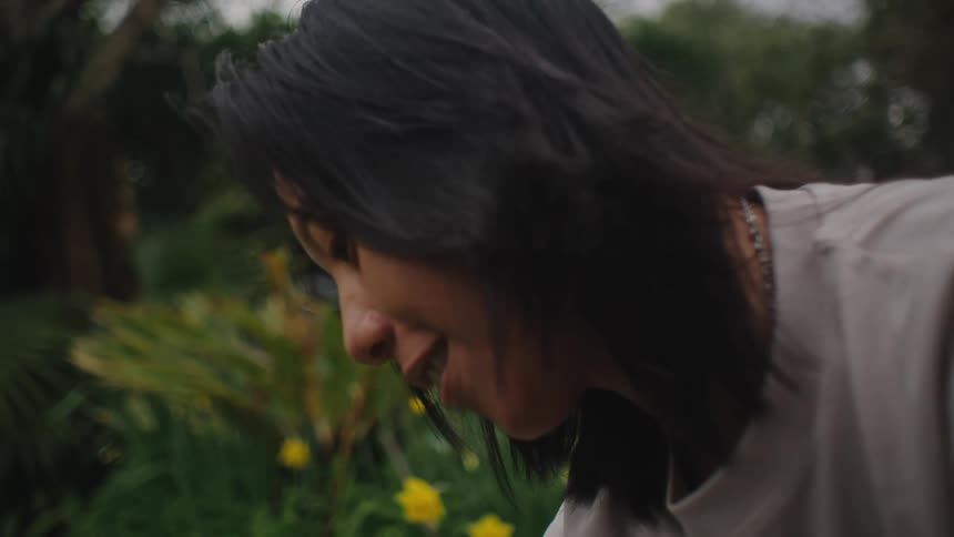 Side portrait of a young woman in the garden with yellow flowers in the background