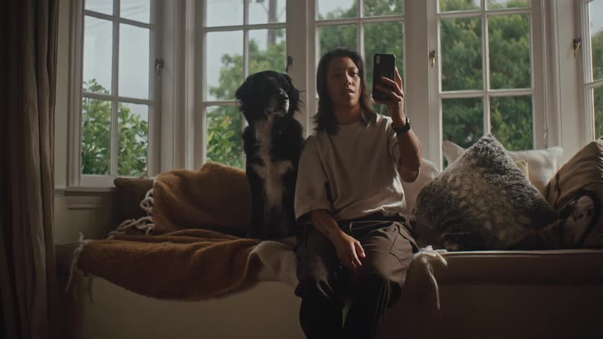 Person interacting with a smartphone while sitting next to a dog