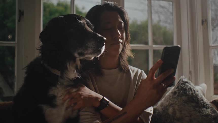 Woman sitting in front of a smartphone next to her dog