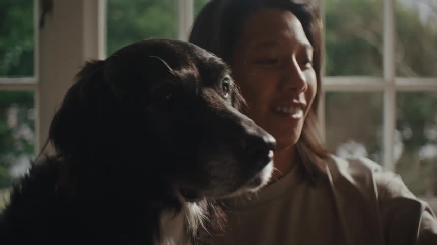 Portrait of a person with a happy facial expression next to a dog indoors