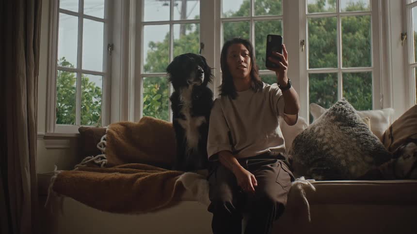A woman video calls her dog from the living room couch