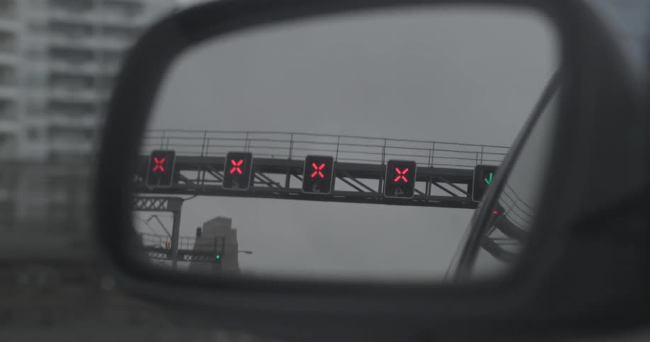 View of a city in a rear view mirror on a cloudy day