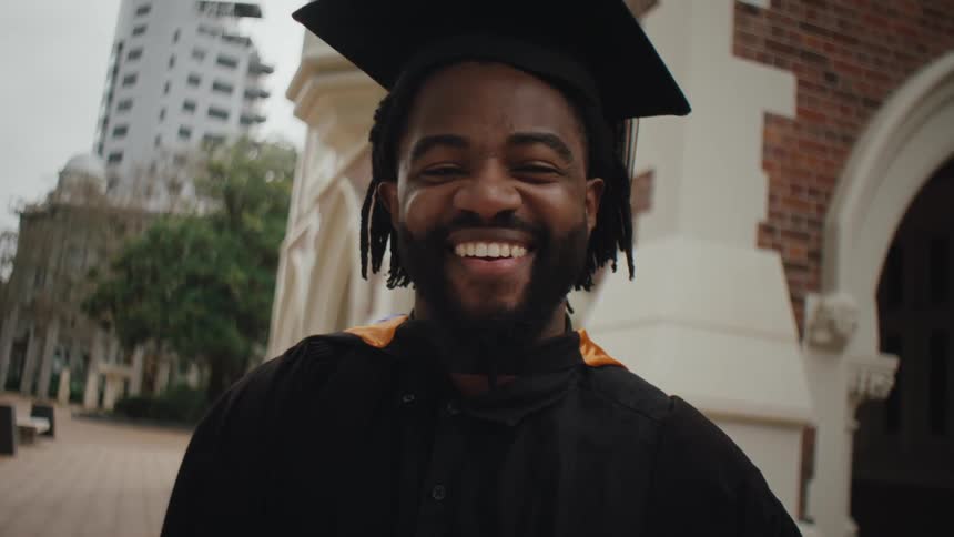 Portrait of a smiling bearded man with graduation gown