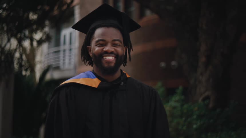 Bearded man with happy facial expression while wearing graduation gown