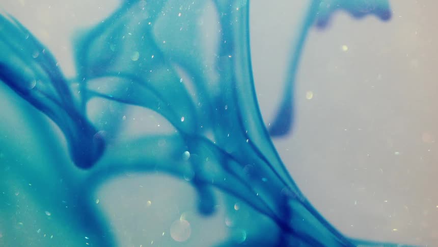 Close up of a clear liquid with an abstract bright blue ink