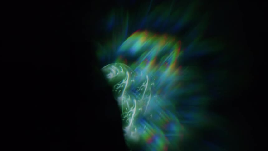 Green shimmery bands of light swirl around each other in darkness