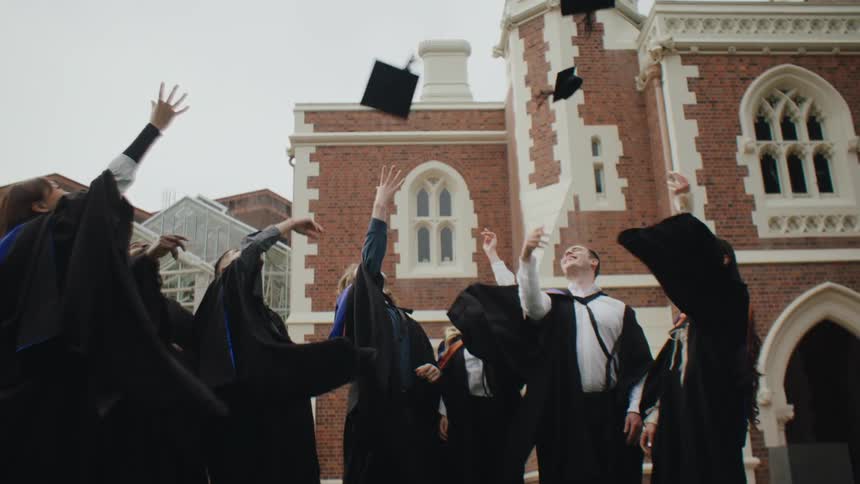 Group of students in graduation gowns throwing their hats in the air