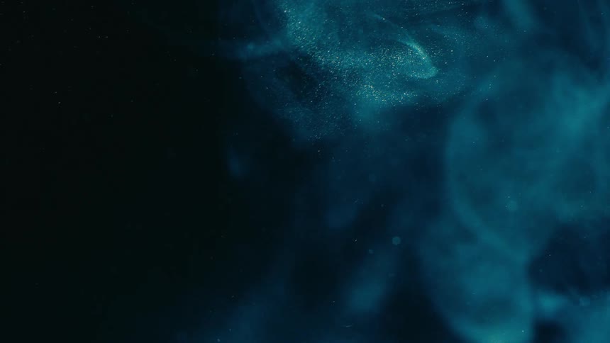 Swirling patterns of blue glitter floating over a dark background