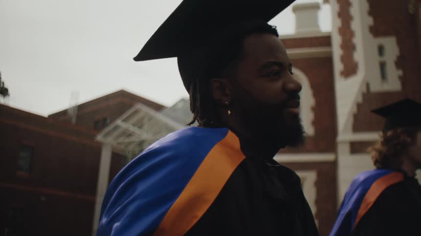Two college men in graduation gowns talking