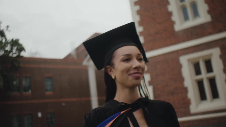 Graduate students wearing cap and gowns hug each other