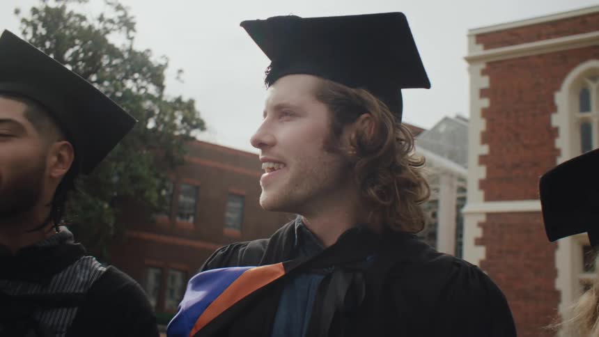 Graduates stand outside together talking
