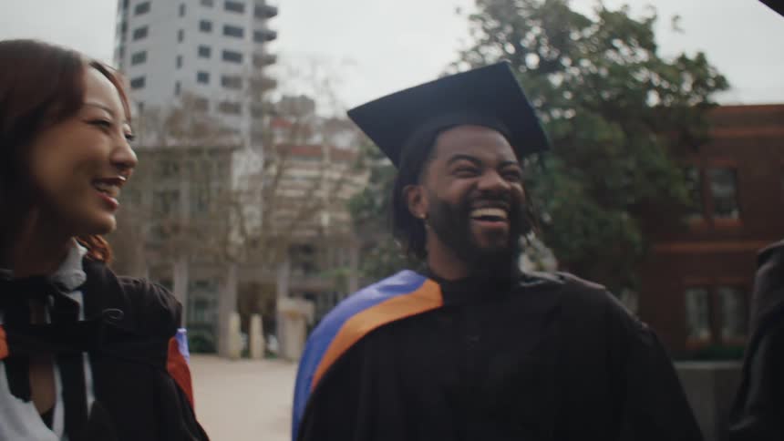 Student friends in graduation attire talking and laughing