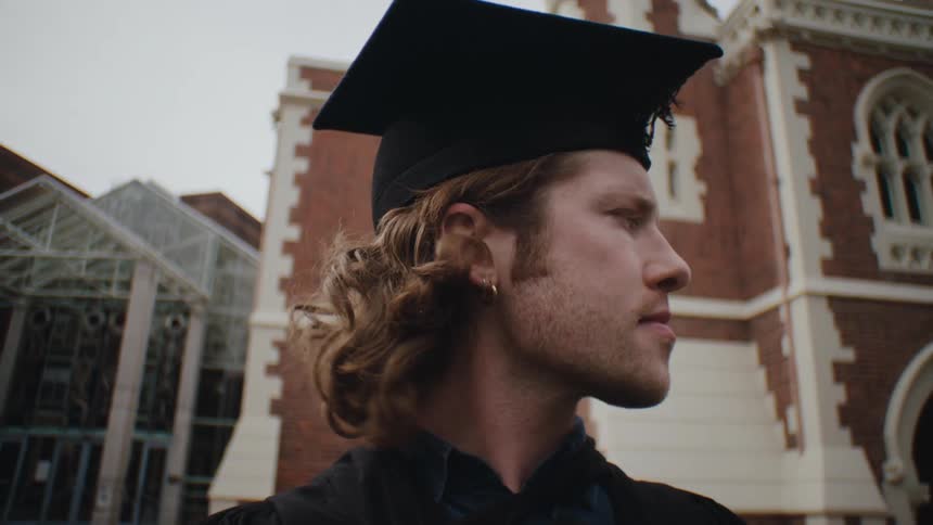 Portrait of a blond man with a beard and a graduation gown