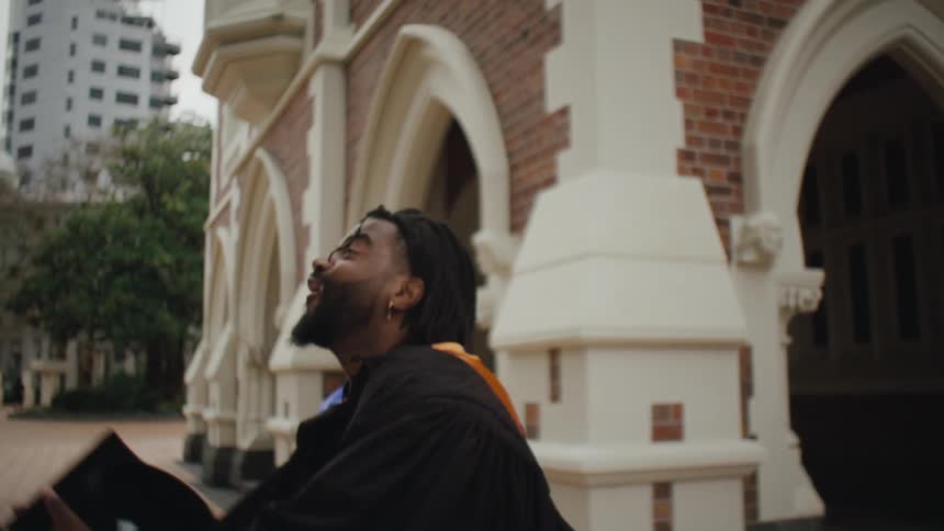 Cheerful man throwing his graduation cap up