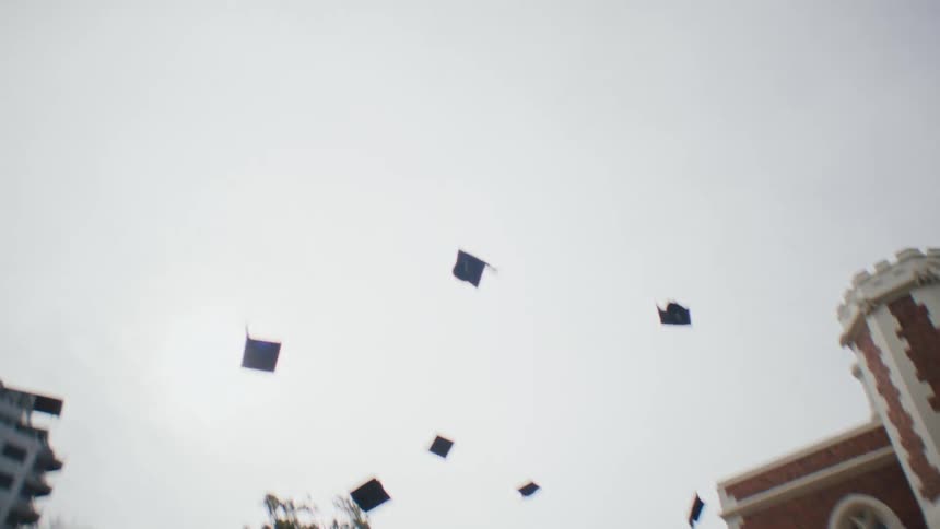 Graduates throw their caps up in the air