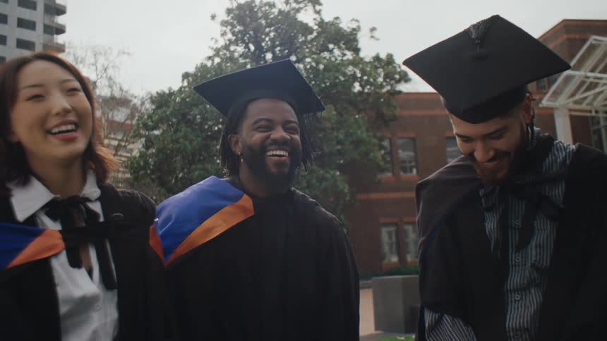 Three happy students with graduation gowns