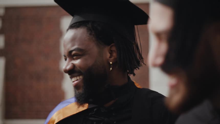 A couple of happy graduate students wearing black academic cap and gown
