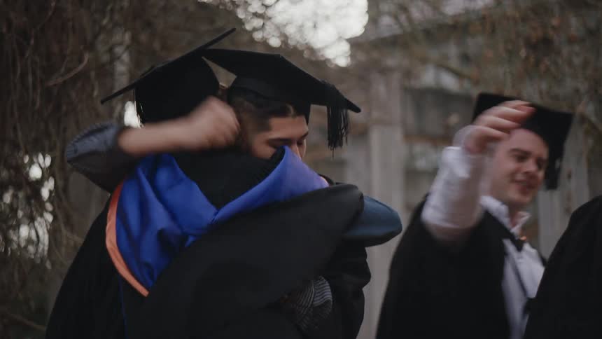 Four men shaking hands while all wearing graduation gowns