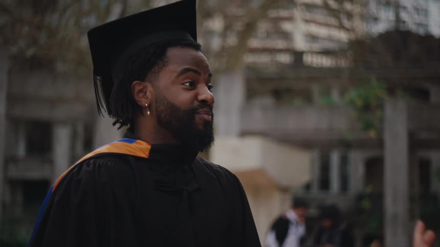 Man in graduation gown talking
