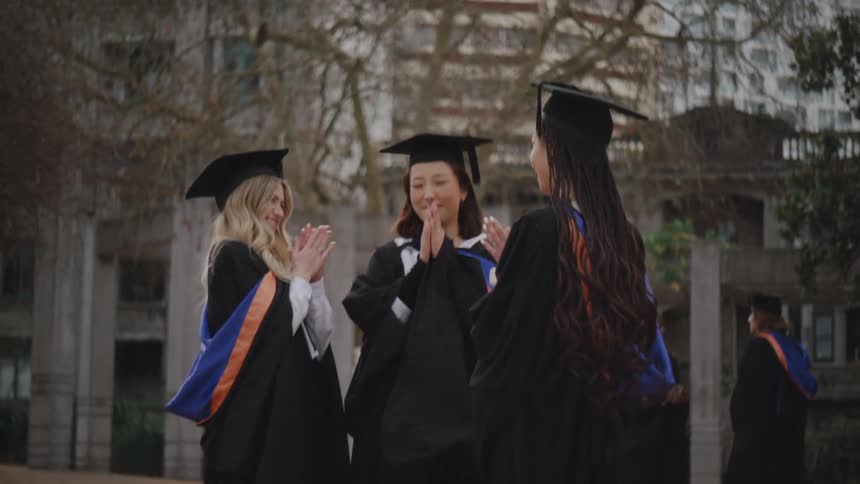 Group of college students in graduation gowns talking