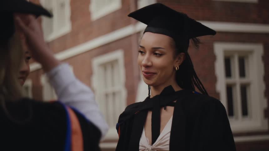 Three women in graduation robes talking to each other