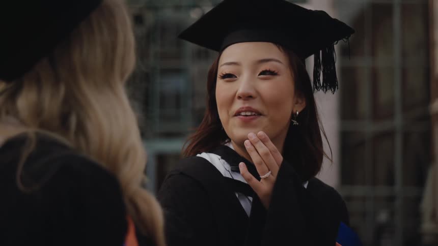 Graduating seniors smile while talking together outside a campus building