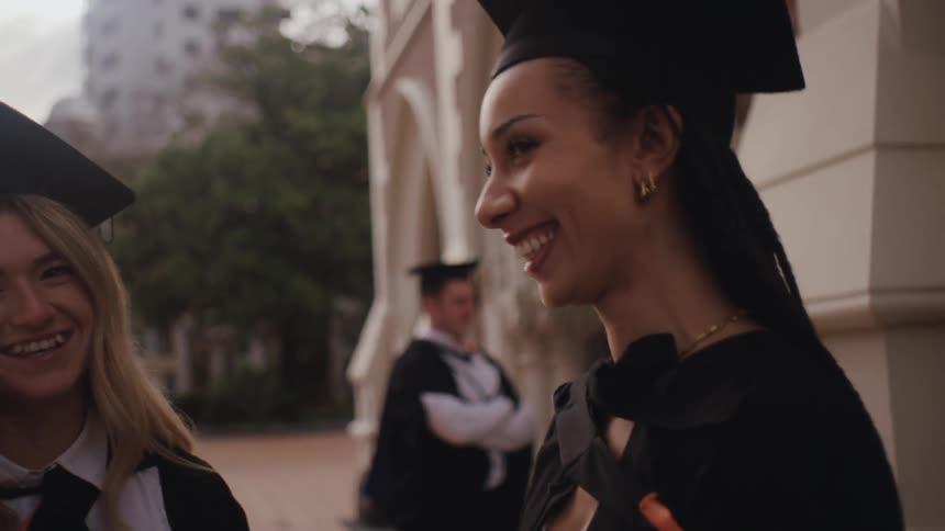 Graduates laugh and talk outside the school