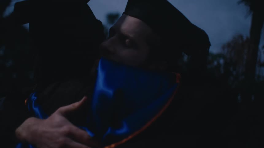 Two friends wearing graduation gowns hugging each other