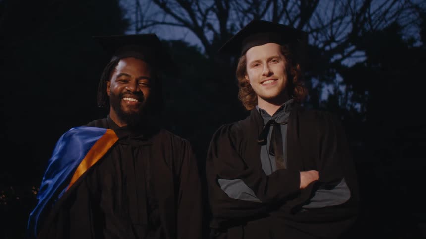 Two men in graduation robes posing smiling