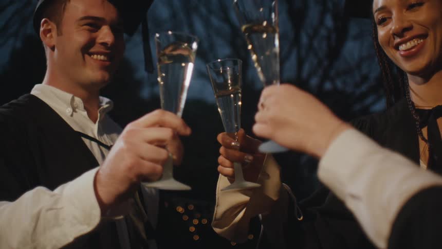 Graduates toasting each other at dusk